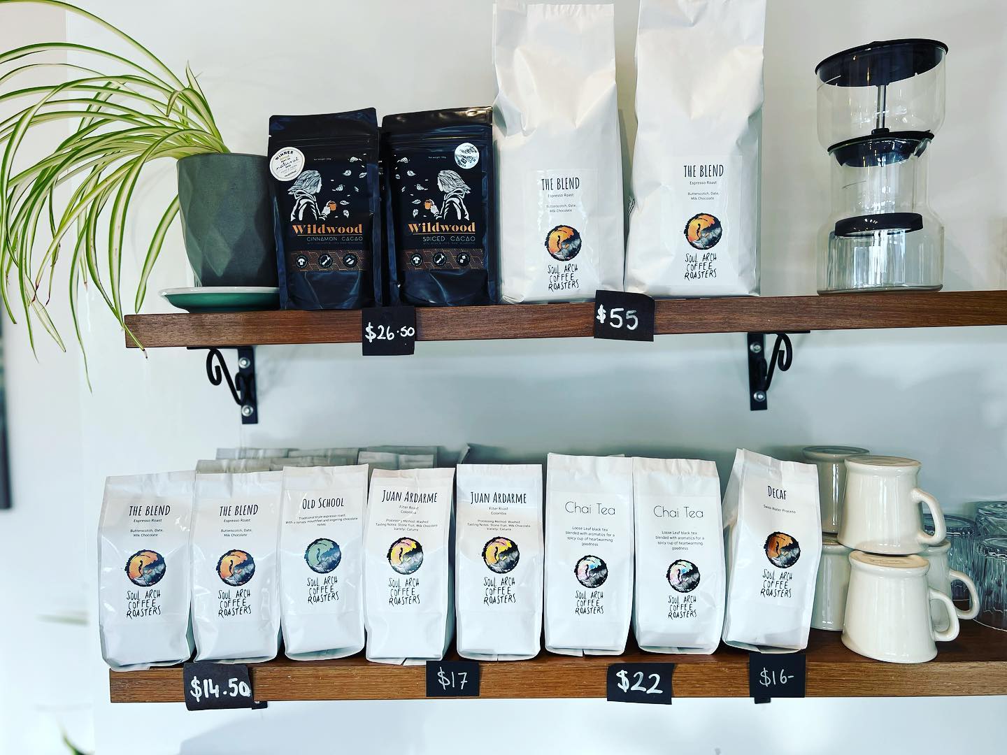 A wooden shelf of white Soul Arch bags: The Blend, Old School, Juan Ardarme, Chai and Decaf